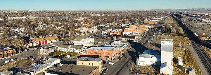 Aerial view of a small city with low-rise buildings, residential neighborhoods, roads, and railroad tracks.