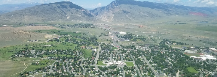 Aerial view of a green valley town surrounded by rugged mountains and open countryside.